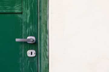 green wooden door beside white wall